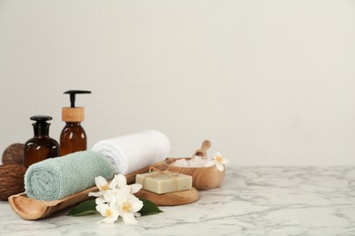 Photo of Composition with beautiful jasmine flowers and skin care products on white marble table, space for text