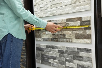 Photo of Man using tape measure while choosing tile in store, closeup