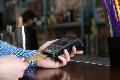 Photo of Man using credit card machine for non cash payment in cafe, closeup. Space for text