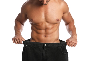 Photo of Young man with slim body in old big size jeans on white background, closeup view