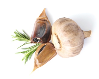 Aged black garlic with rosemary on white background, view from above