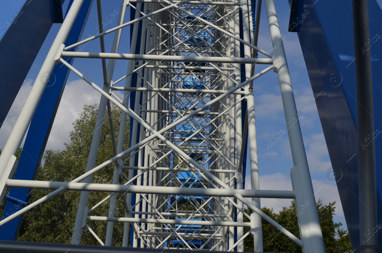 Photo of Large Ferris wheel with blue cabins in amusement park.
