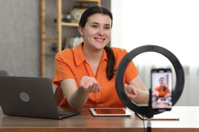 Photo of Smiling technology blogger with tablets recording video review at home