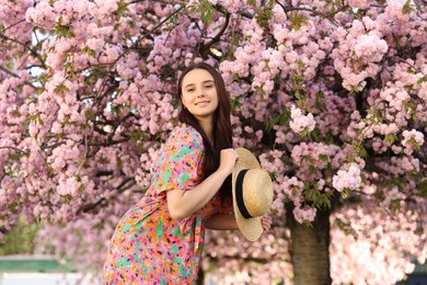 Photo of Beautiful woman with straw hat near blossoming tree on spring day