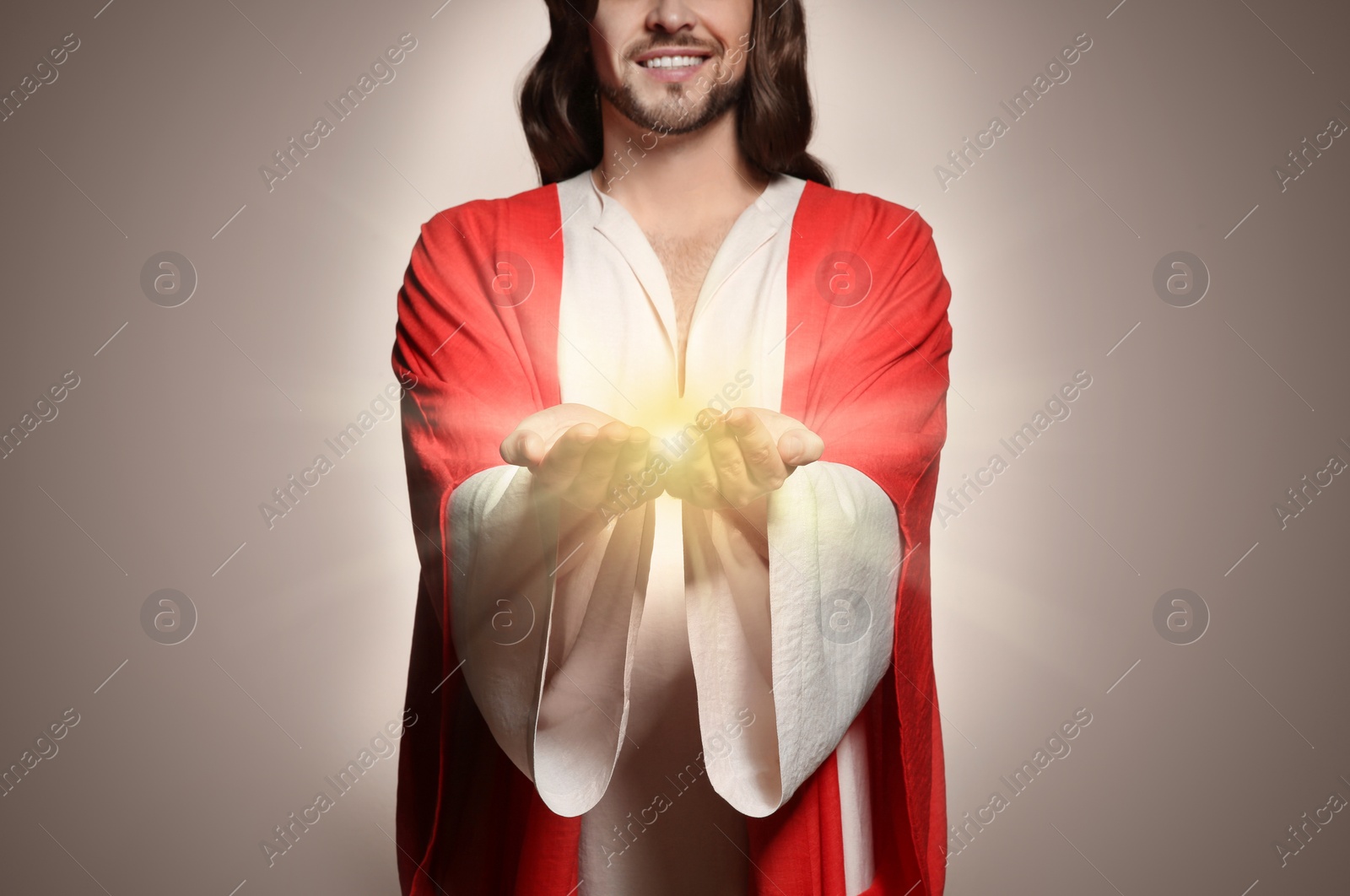 Image of Jesus Christ on beige background, closeup. Miraculous light in hands