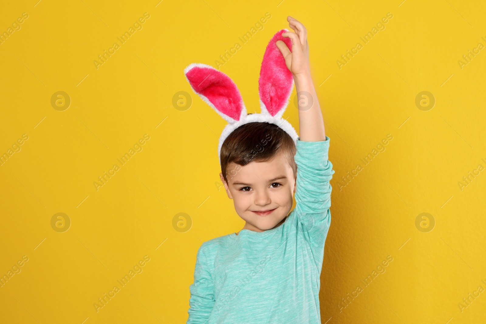 Photo of Portrait of little boy in Easter bunny ears headband on color background