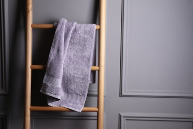 Terry towel on wooden ladder indoors, space for text