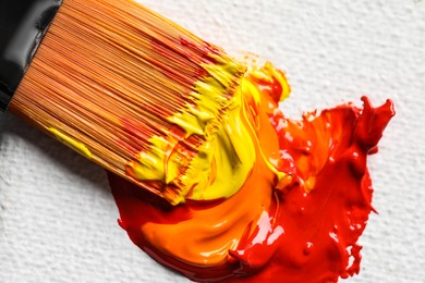 Photo of Beautiful colorful oil paints and brush on white canvas, closeup