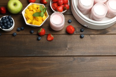 Photo of Modern yogurt maker with full jars and different fruits on wooden table, flat lay. Space for text