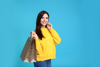 Photo of Portrait of young woman with paper bags on blue background