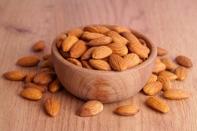 Photo of Tasty almonds in bowl on wooden table