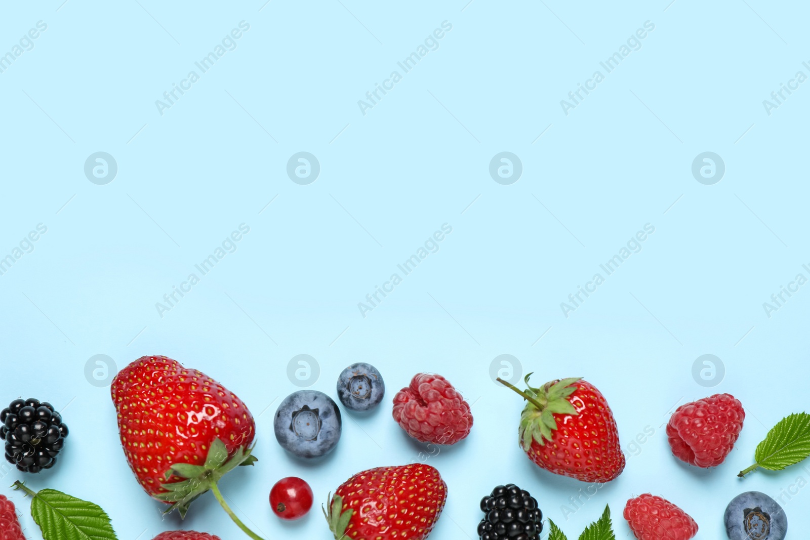 Photo of Different fresh berries on light blue background, flat lay. Space for text