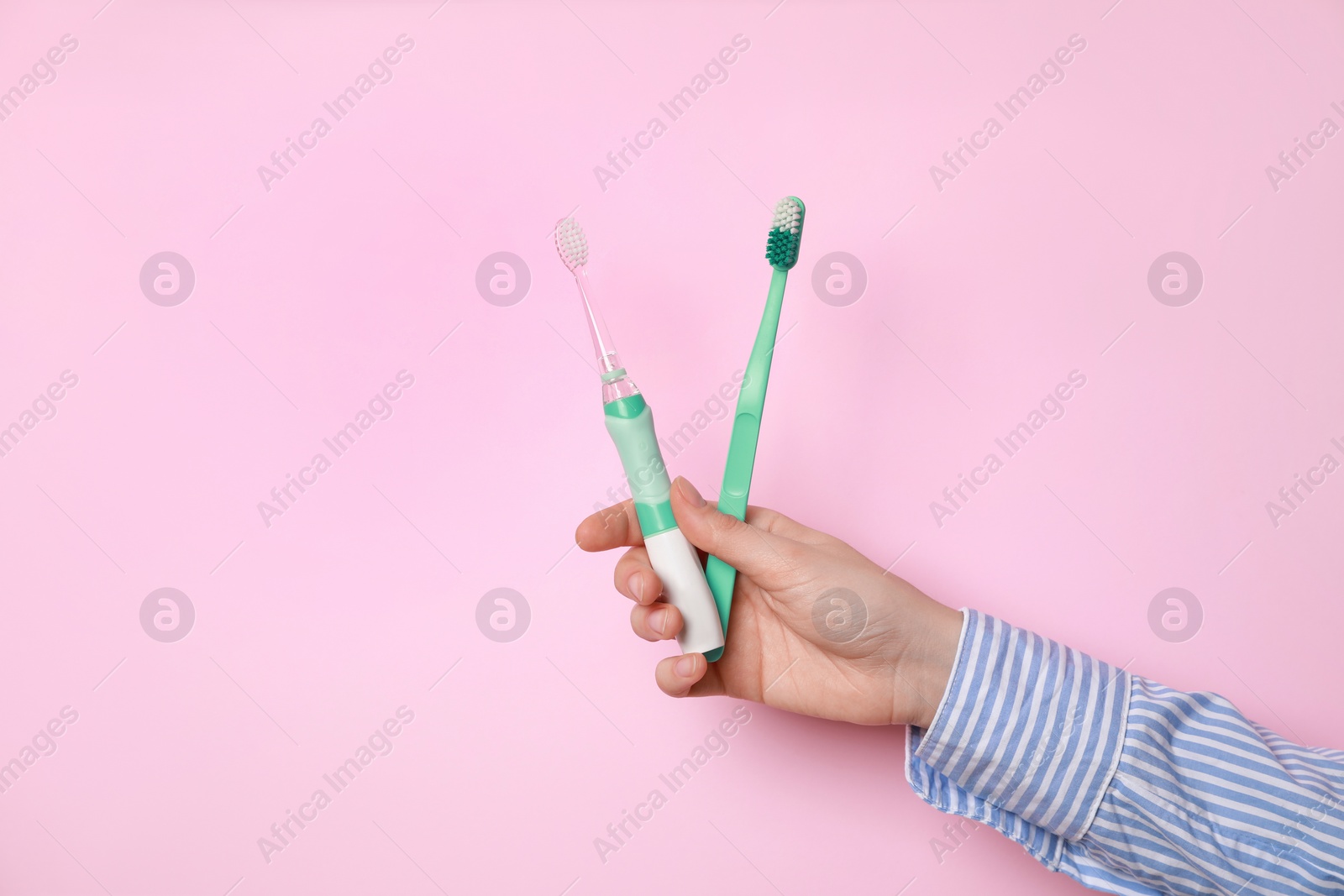 Photo of Woman holding electric and plastic toothbrushes on pink background, closeup