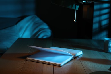 Photo of Open book on wooden table at night