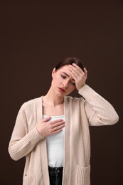 Photo of Woman suffering from headache on brown background. Cold symptoms