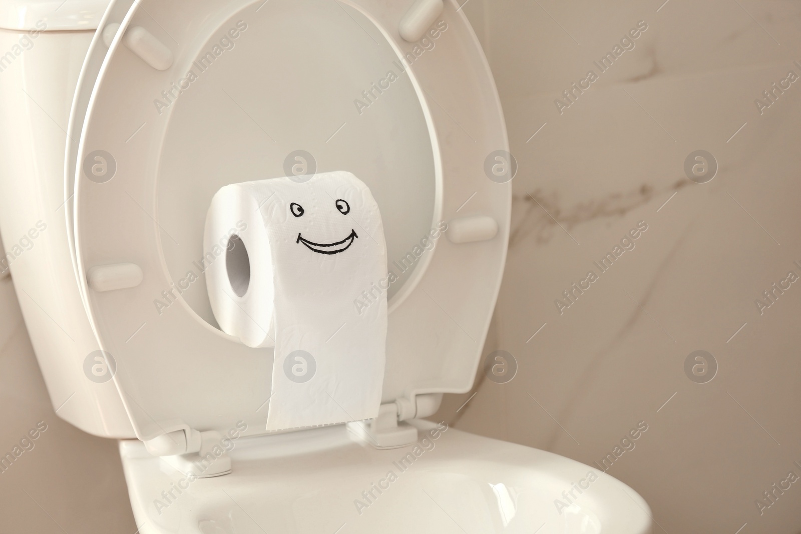 Photo of Roll of paper with funny face on toilet bowl in bathroom