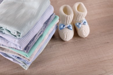 Photo of Stack of baby boy's clothes and booties on wooden table, above view