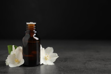 Essential oil and jasmine flowers on grey table. Space for text