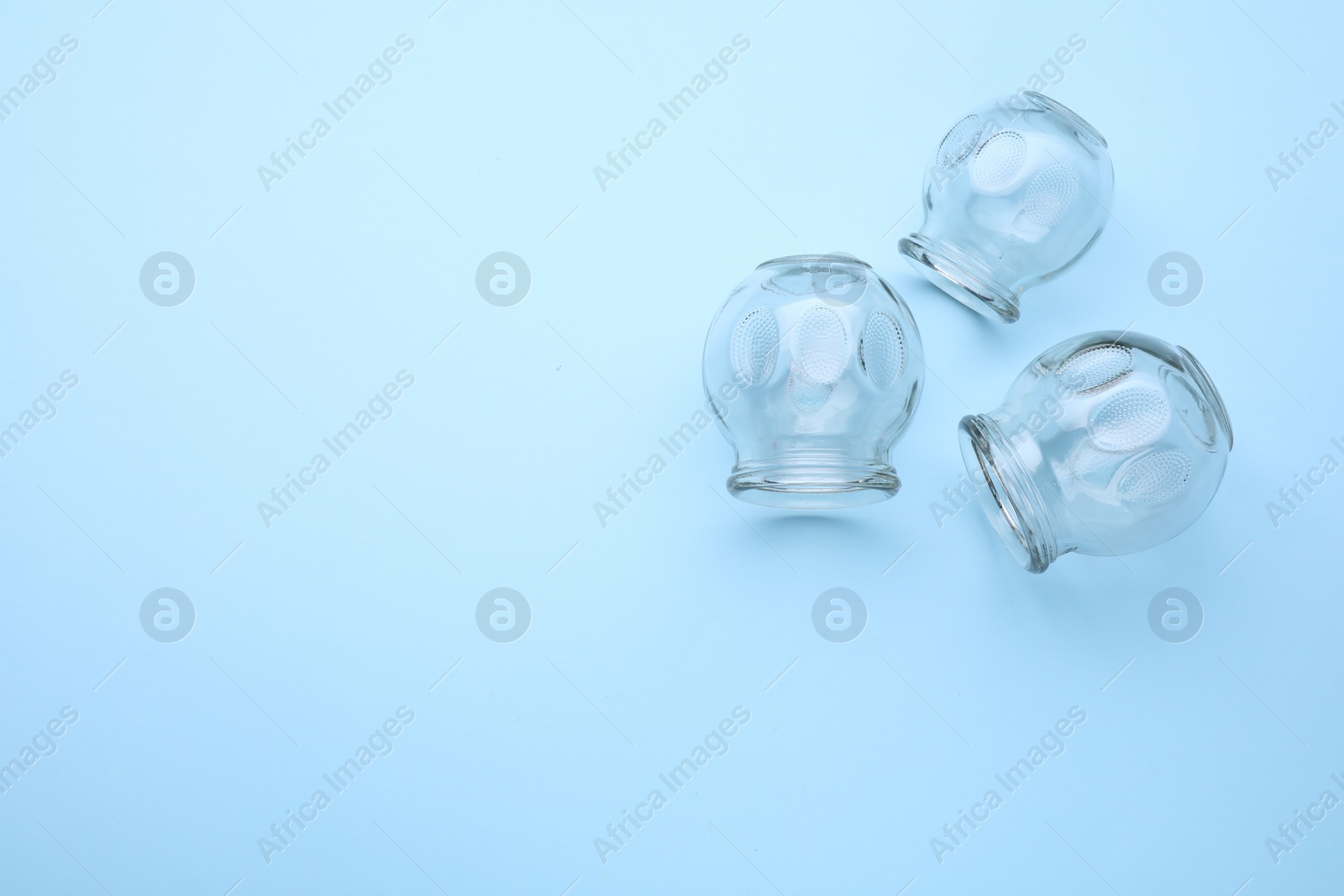 Photo of Glass cups on light blue background, flat lay with space for text. Cupping therapy