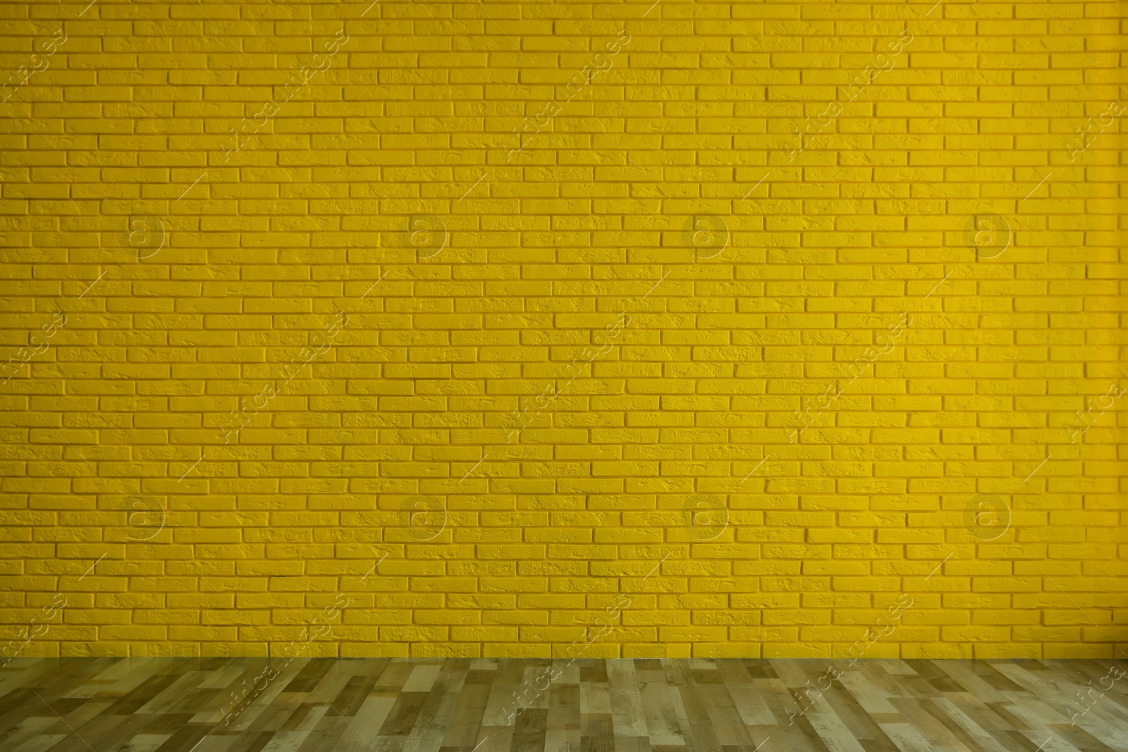 Photo of Empty room with yellow brick wall and wooden floor