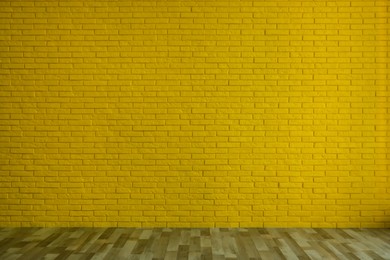Photo of Empty room with yellow brick wall and wooden floor