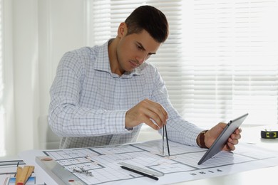 Photo of Architect working with construction drawings in office