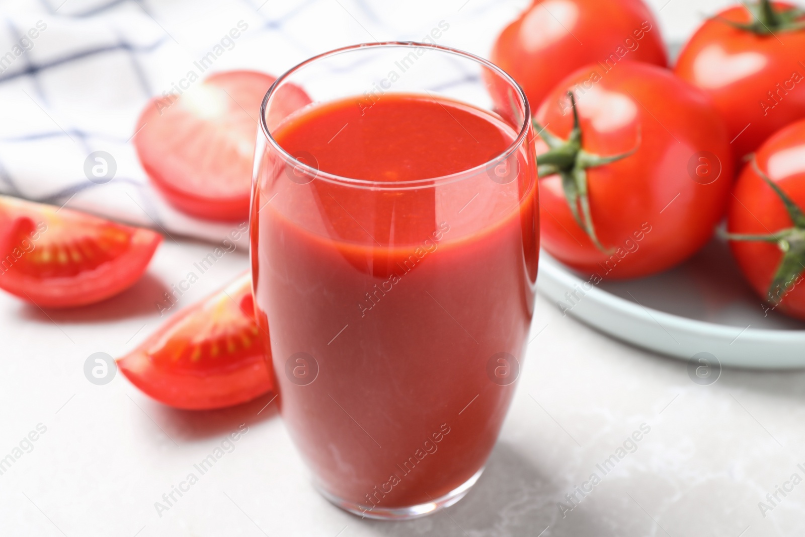 Photo of Delicious fresh tomato juice on light grey marble table table, closeup