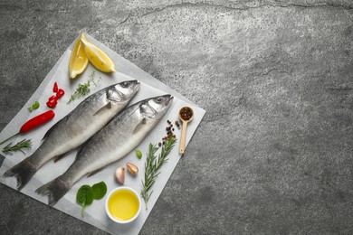 Sea bass fish and ingredients on grey table, top view. Space for text