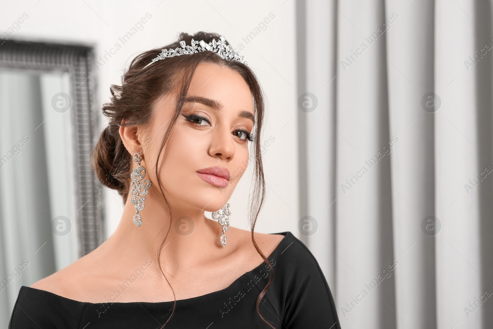 Photo of Beautiful young woman wearing luxurious tiara indoors, space for text