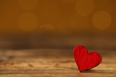 Red decorative heart on wooden table against yellow background, space for text. Valentine's Day