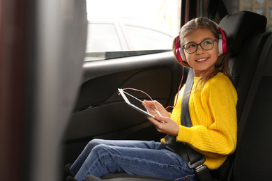 Photo of Cute little girl listening to audiobook in car