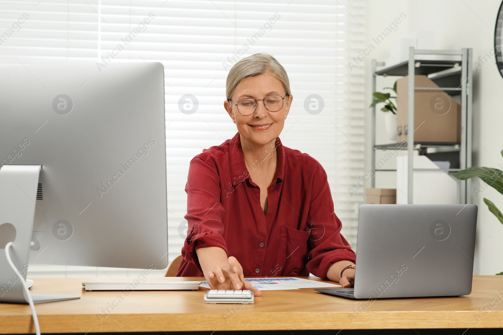 Photo of Senior accountant working at wooden desk in office