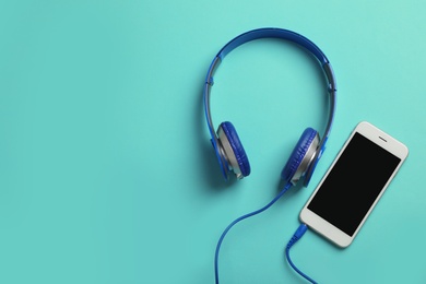 Photo of Stylish headphones and modern phone on color background, flat lay. Space for text