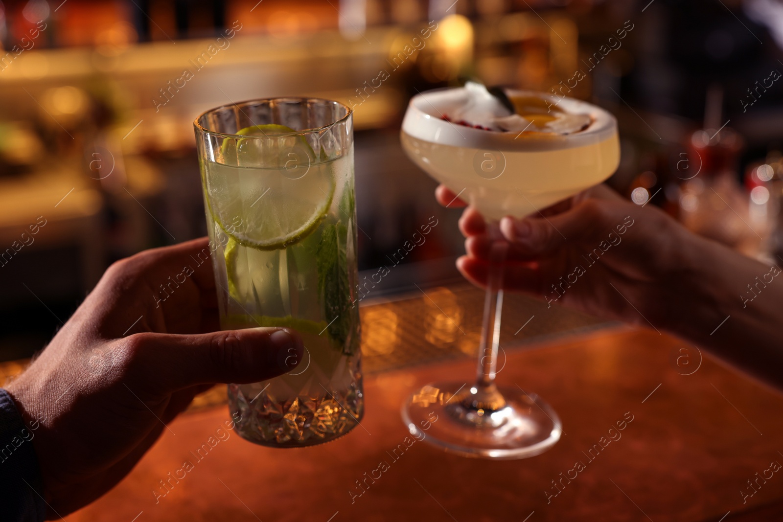 Photo of People holding glasses with fresh cocktails at bar counter, closeup