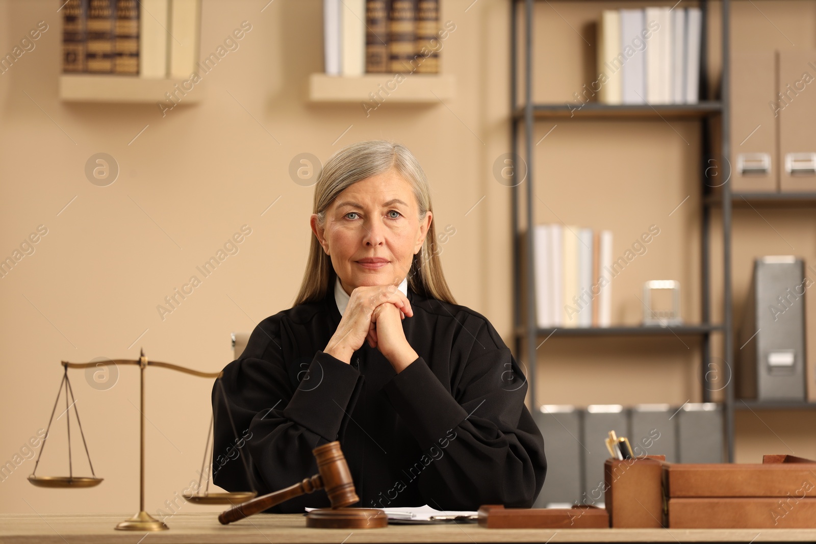 Photo of Judge in court dress working at table indoors