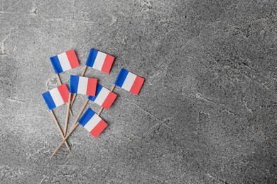 Photo of Small paper flags of France on grey table, flat lay. Space for text