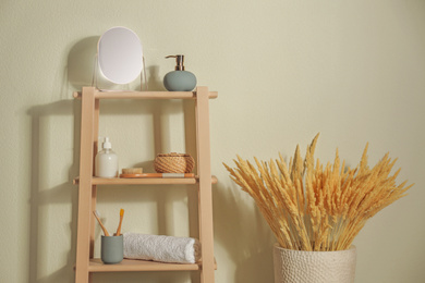Photo of Wooden shelving unit with toiletries near light wall indoors. Bathroom interior element