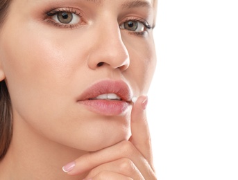 Young woman with cold sore applying cream on lips against white background, closeup