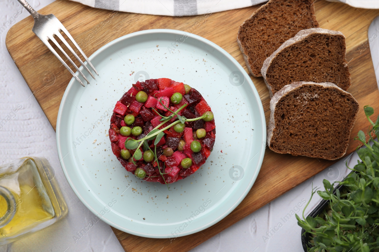 Photo of Delicious vinaigrette salad and slices of bread on white textured table, flat lay