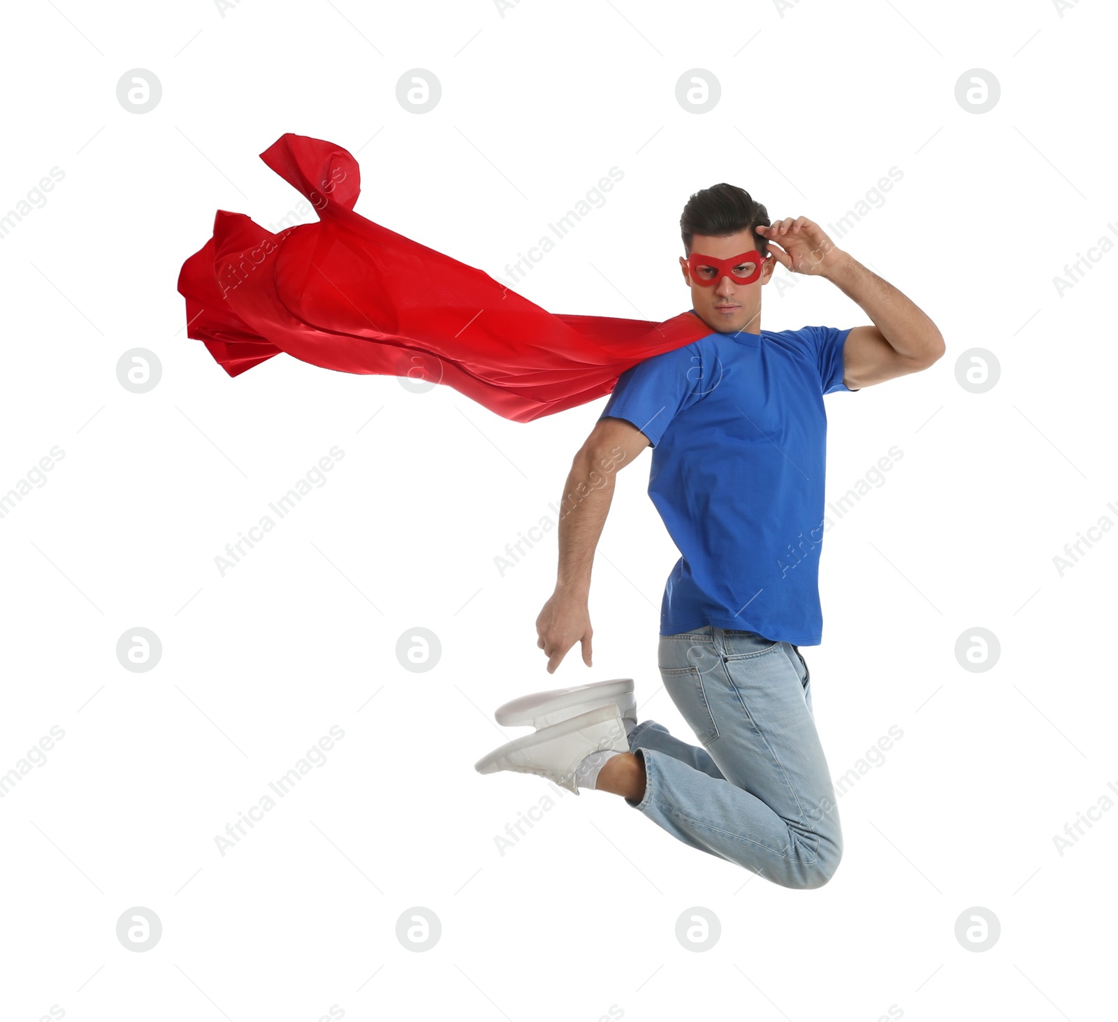 Photo of Man in superhero cape and mask jumping on white background