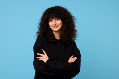 Young woman in stylish black sweater on light blue background