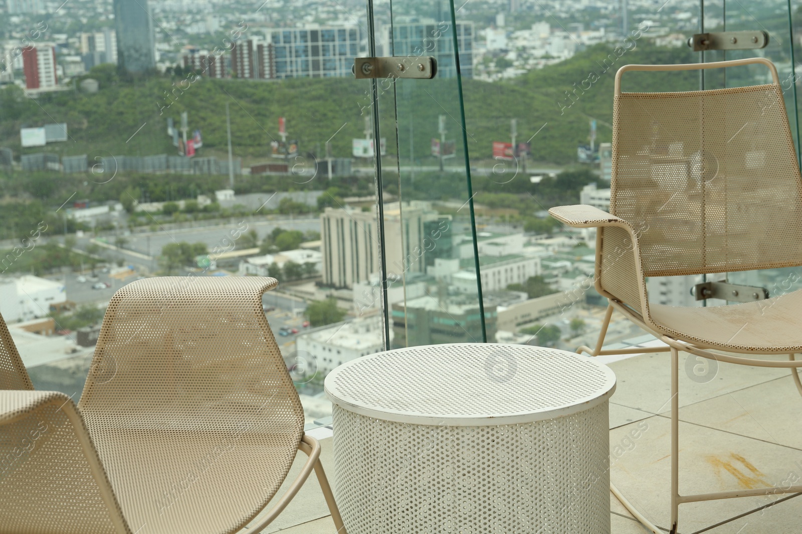 Photo of Coffee table and beige chairs against picturesque landscape of city in cafe