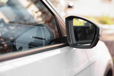 Photo of Side view mirror of modern car on blurred background, closeup