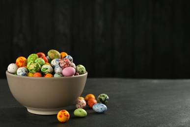 Ceramic bowl with delicious candies on dark grey table, space for text. Cooking utensil