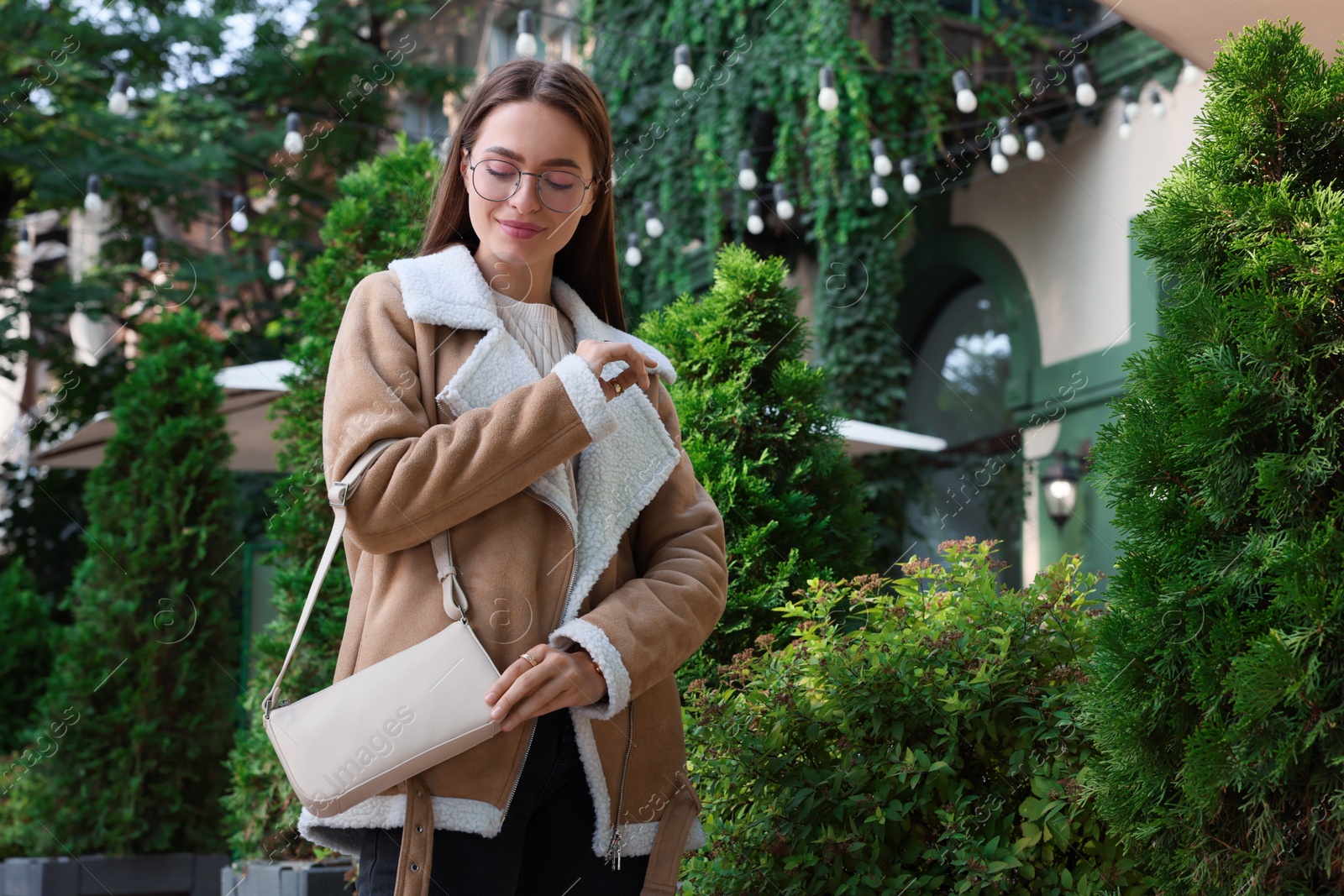 Photo of Fashionable young woman with stylish bag on city street. Space for text