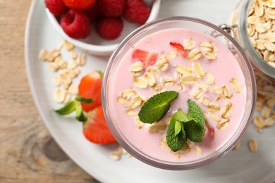 Photo of Glass of tasty berry smoothie with oatmeal on wooden table, top view