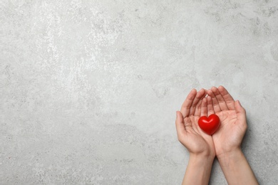 Photo of Woman holding heart on grey stone background, top view with space for text. Donation concept