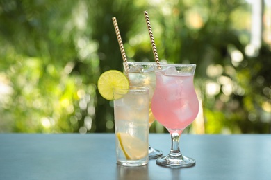 Delicious refreshing drinks in glasses on grey table outdoors