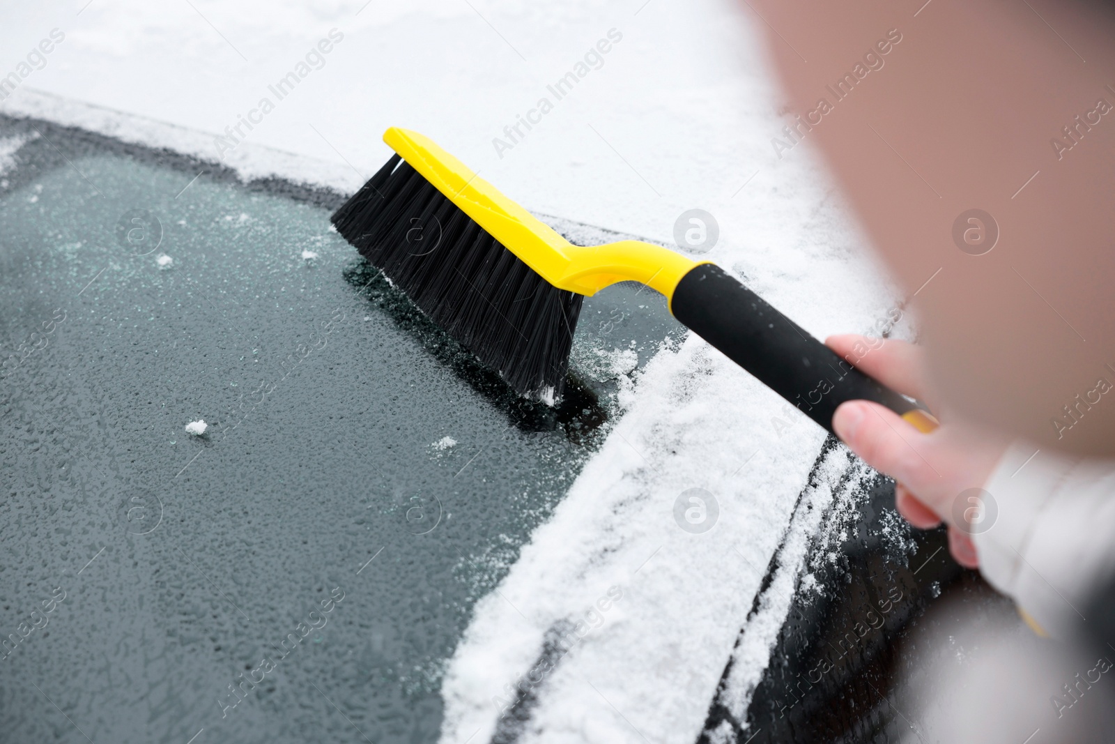 Photo of Man cleaning snow from car windshield outdoors, closeup