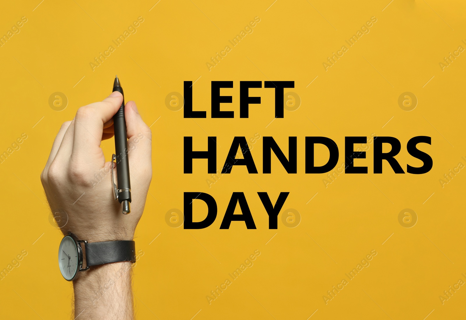 Image of Left-handed man holding pen on yellow background, closeup 